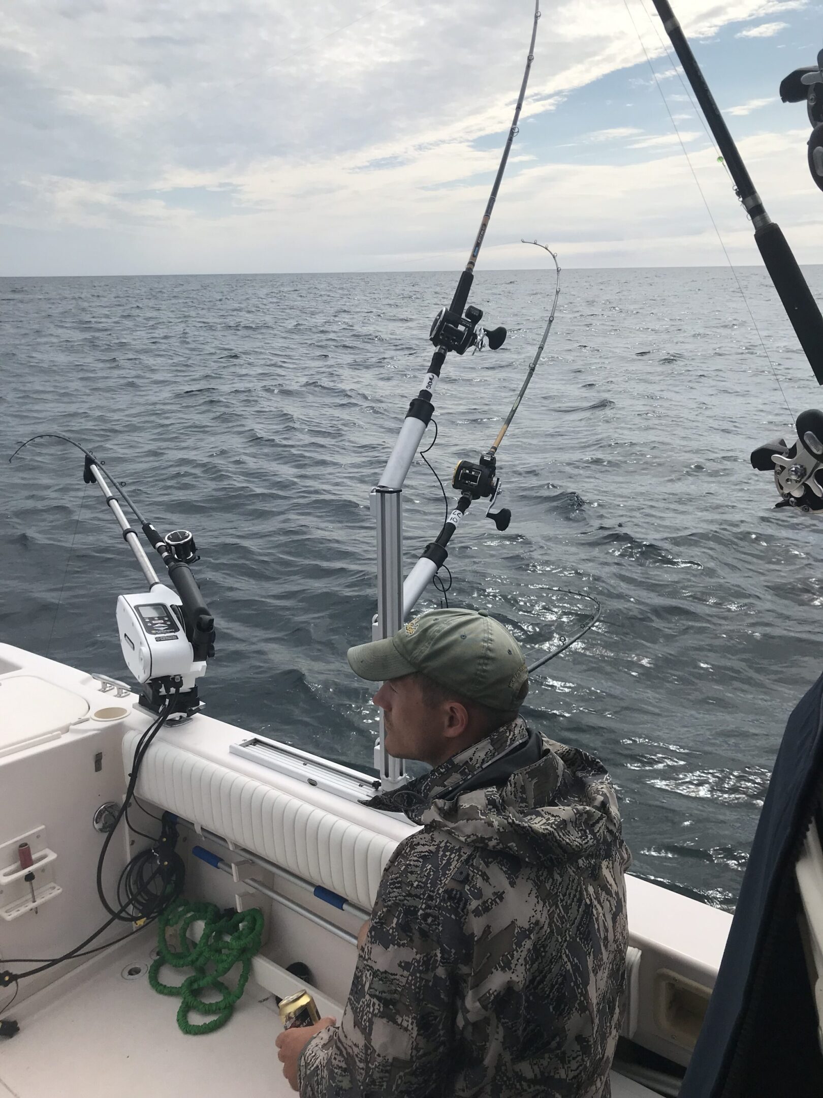 A person fishing on a boat with multiple fishing rods in the ocean.