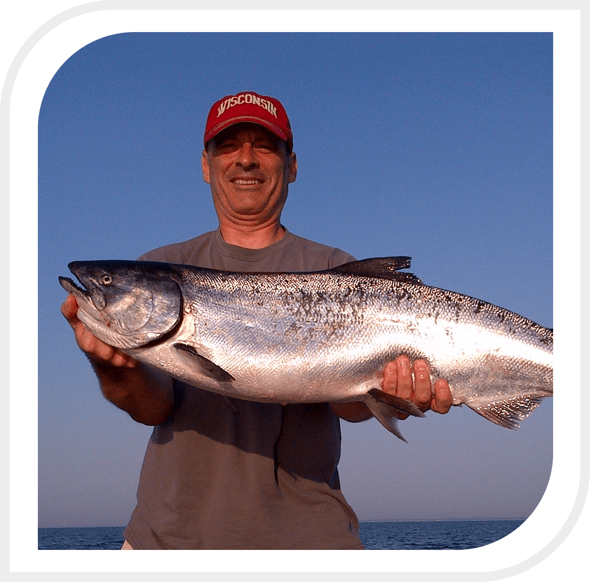 Man holding a large fish with a clear sky background.