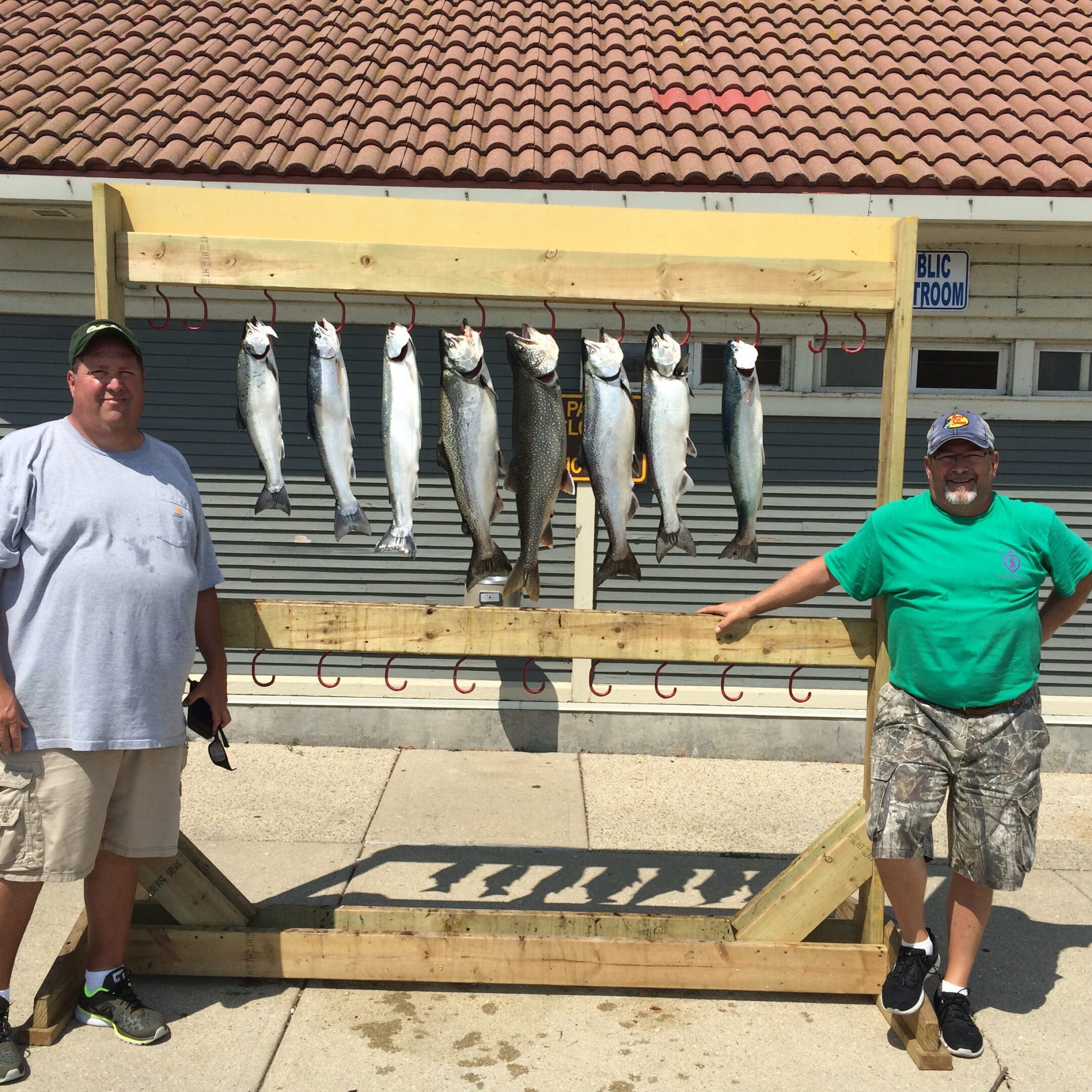 Two men standing beside a fish display with caught fish hanging.