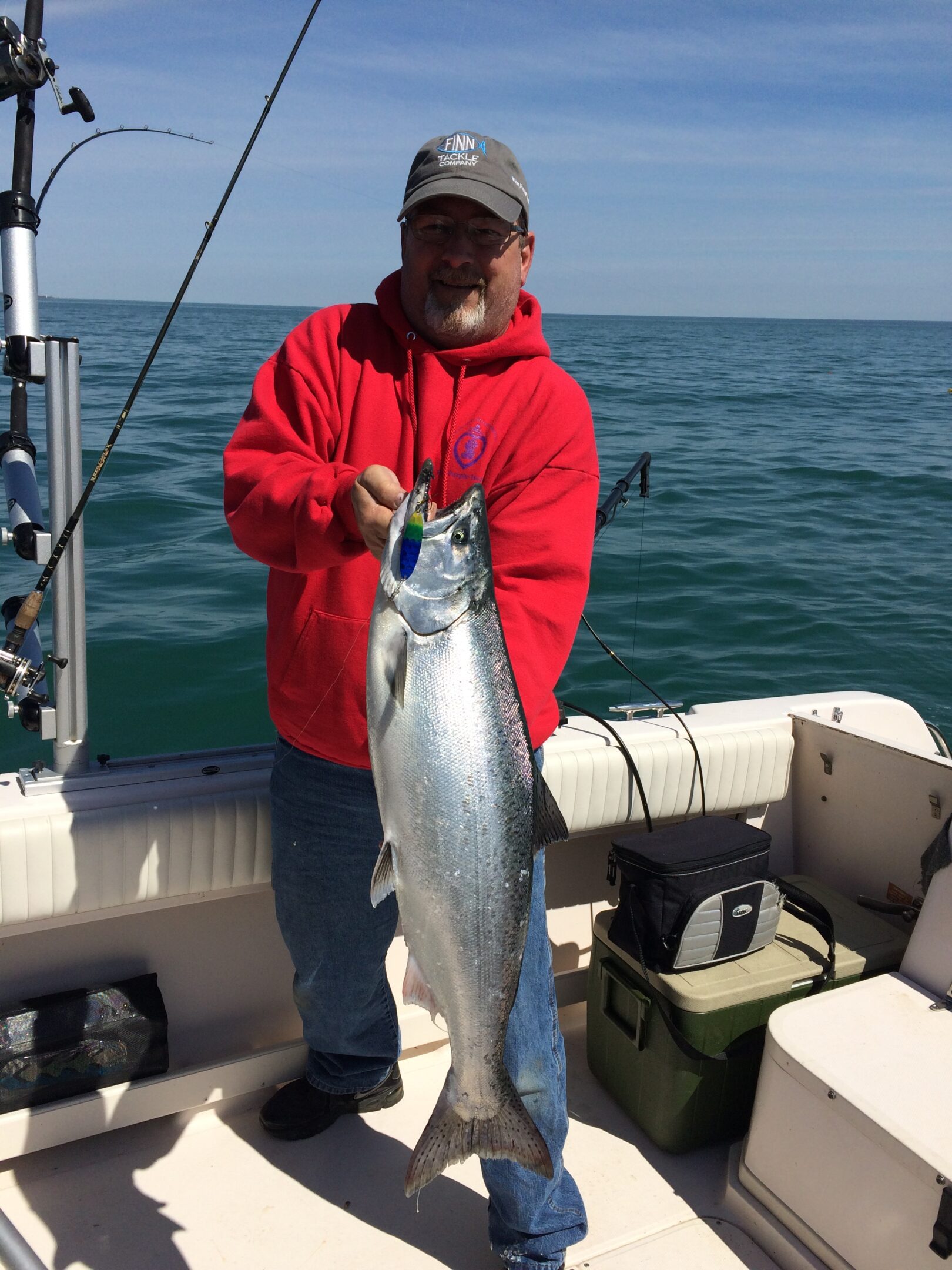 A person in a red jacket holding a large fish on a boat.
