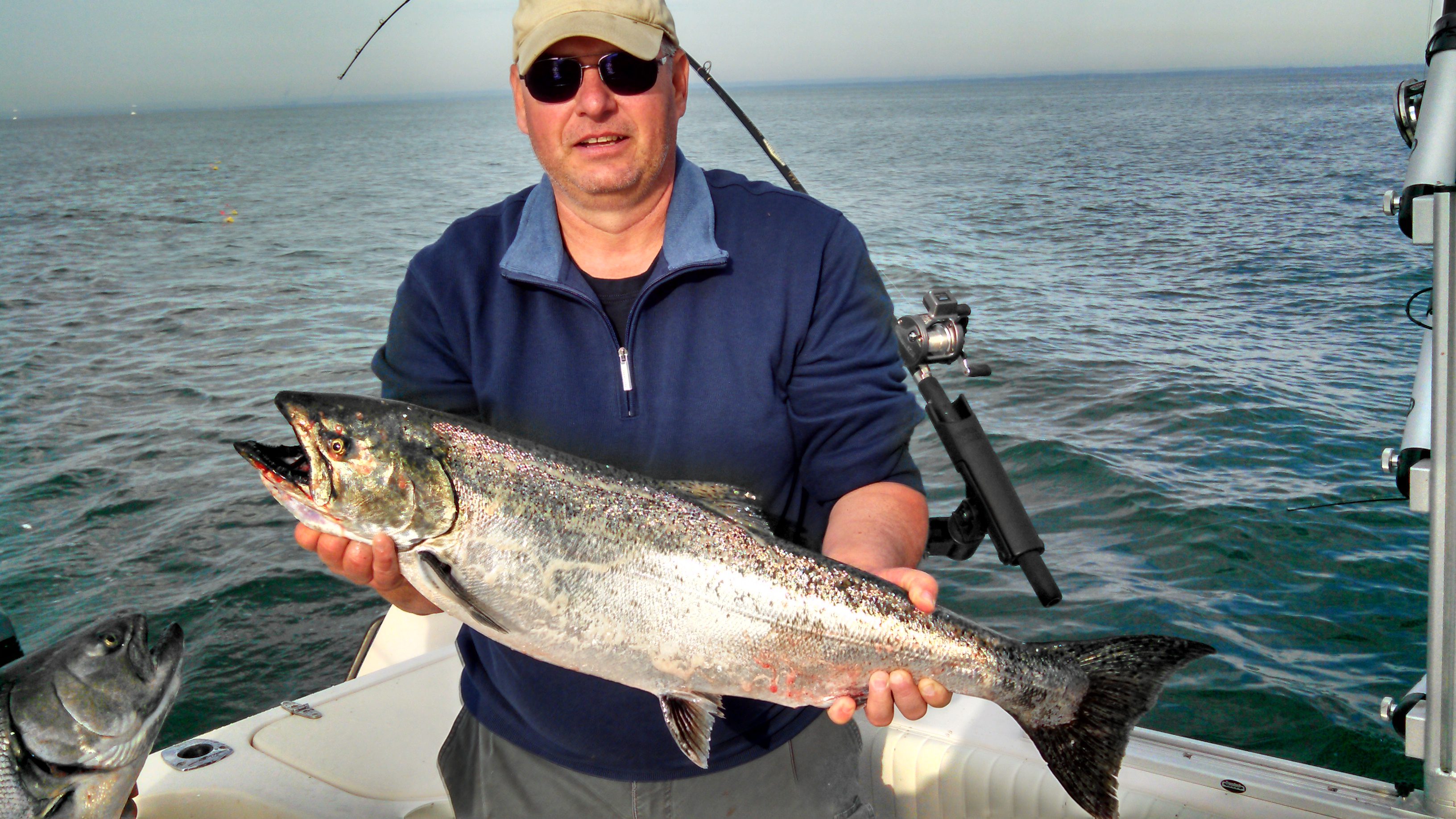 A man holding a large fish on a boat at sea.