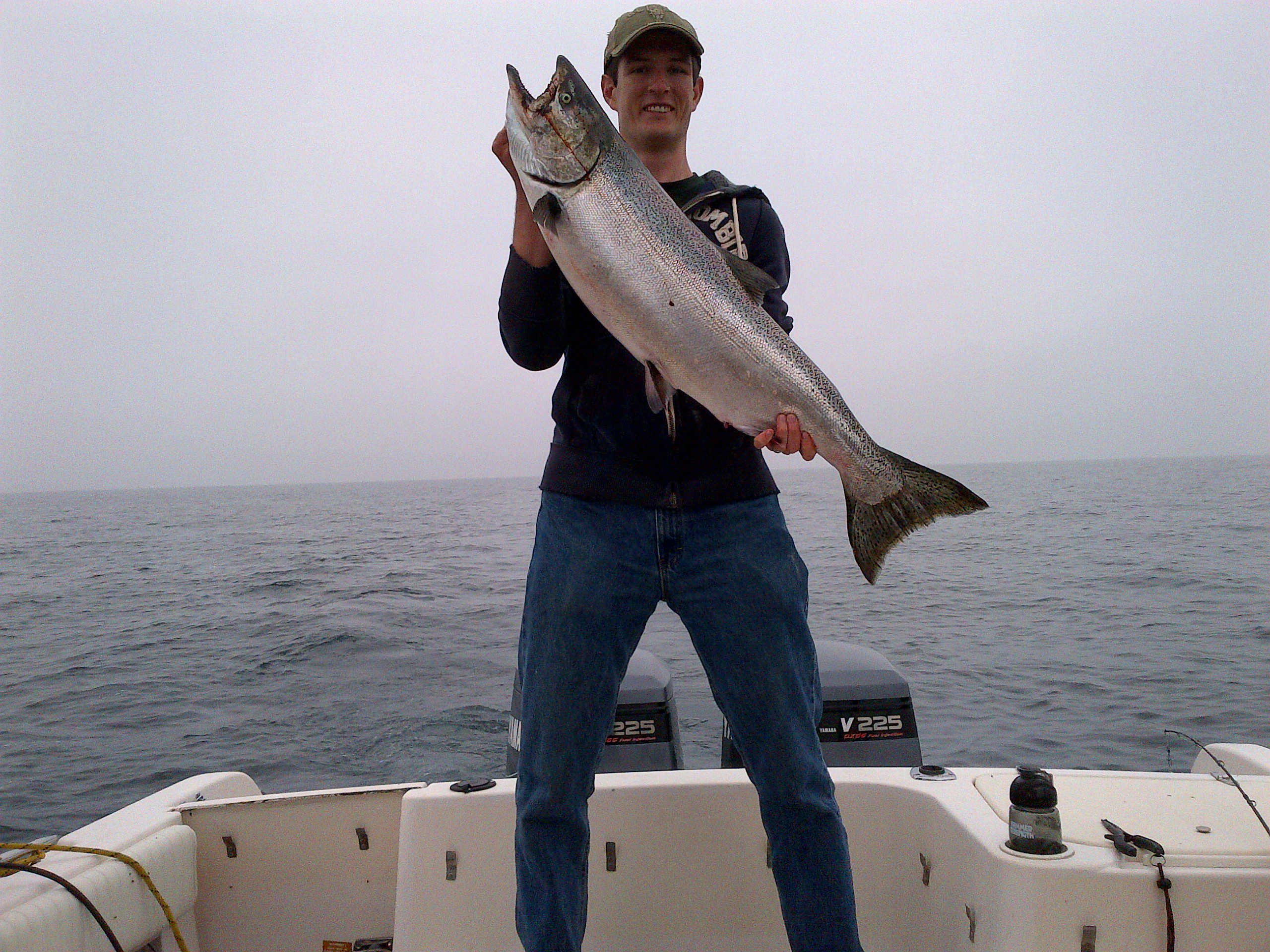 A man holding a large fish on a boat at sea.