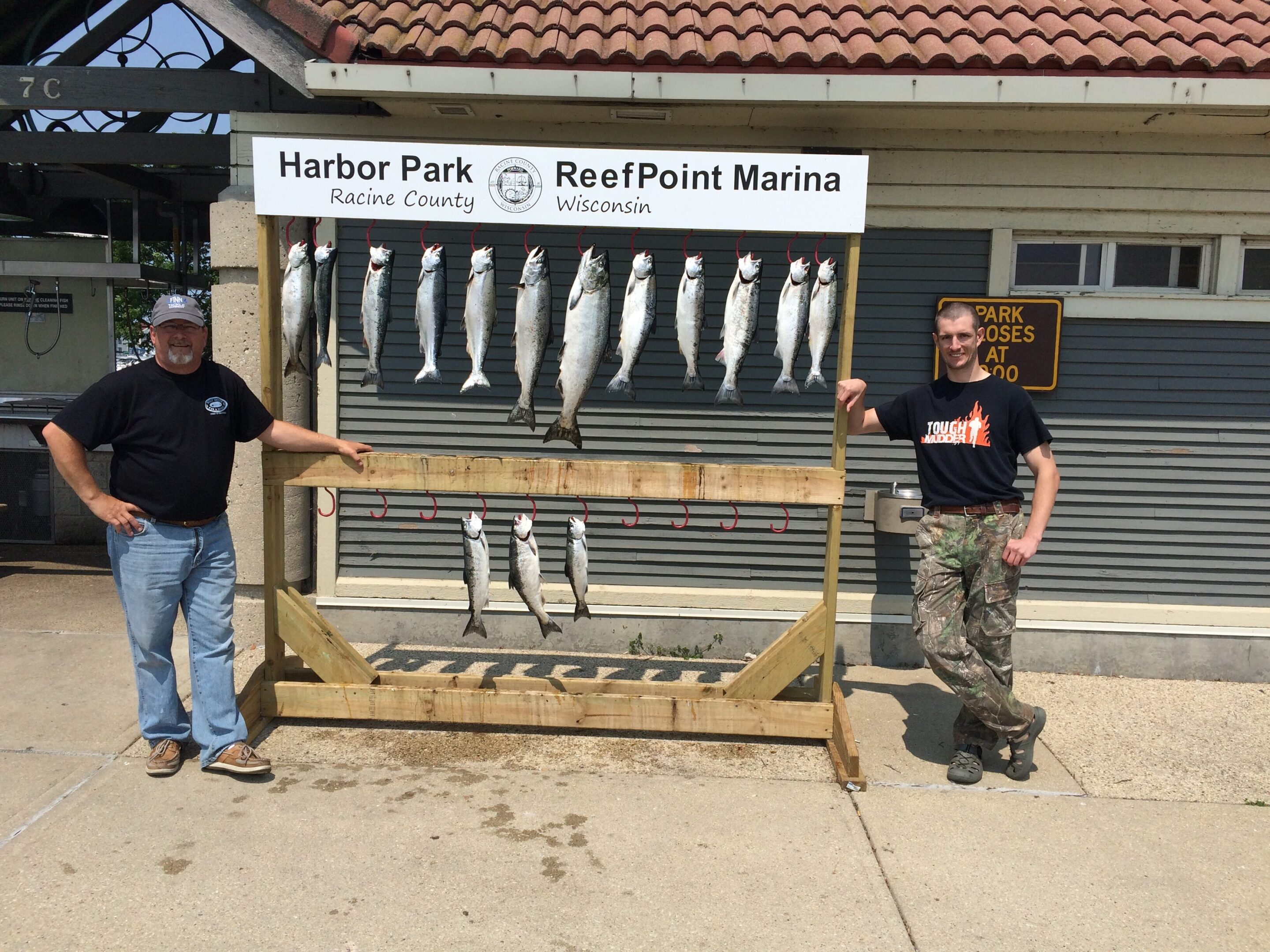 Two people stand beside a display of caught fish at Harbor Park RoofPoint Marina.