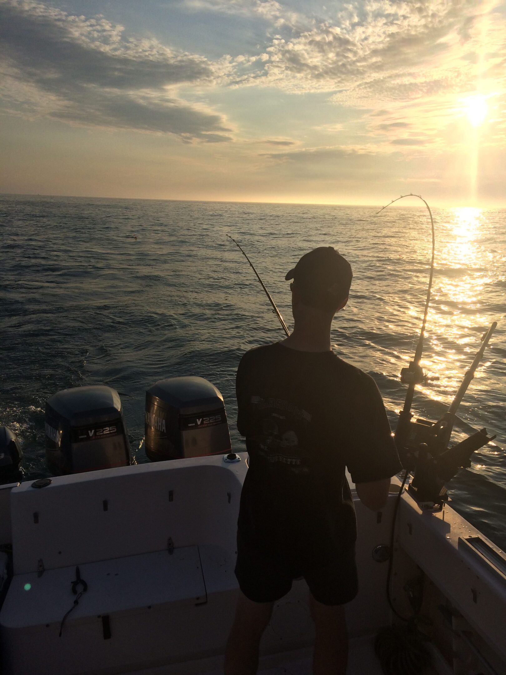 Person fishing on a boat at sunset.
