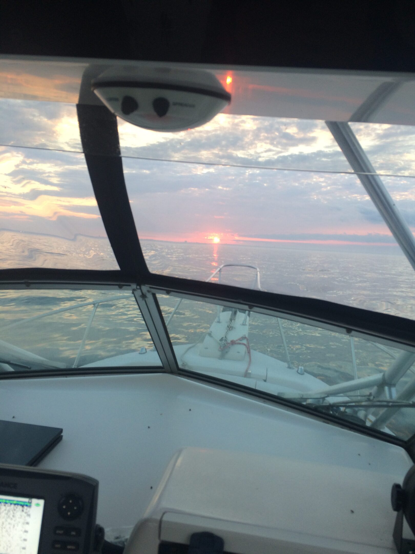 View from a boat cockpit at sunset on calm waters.