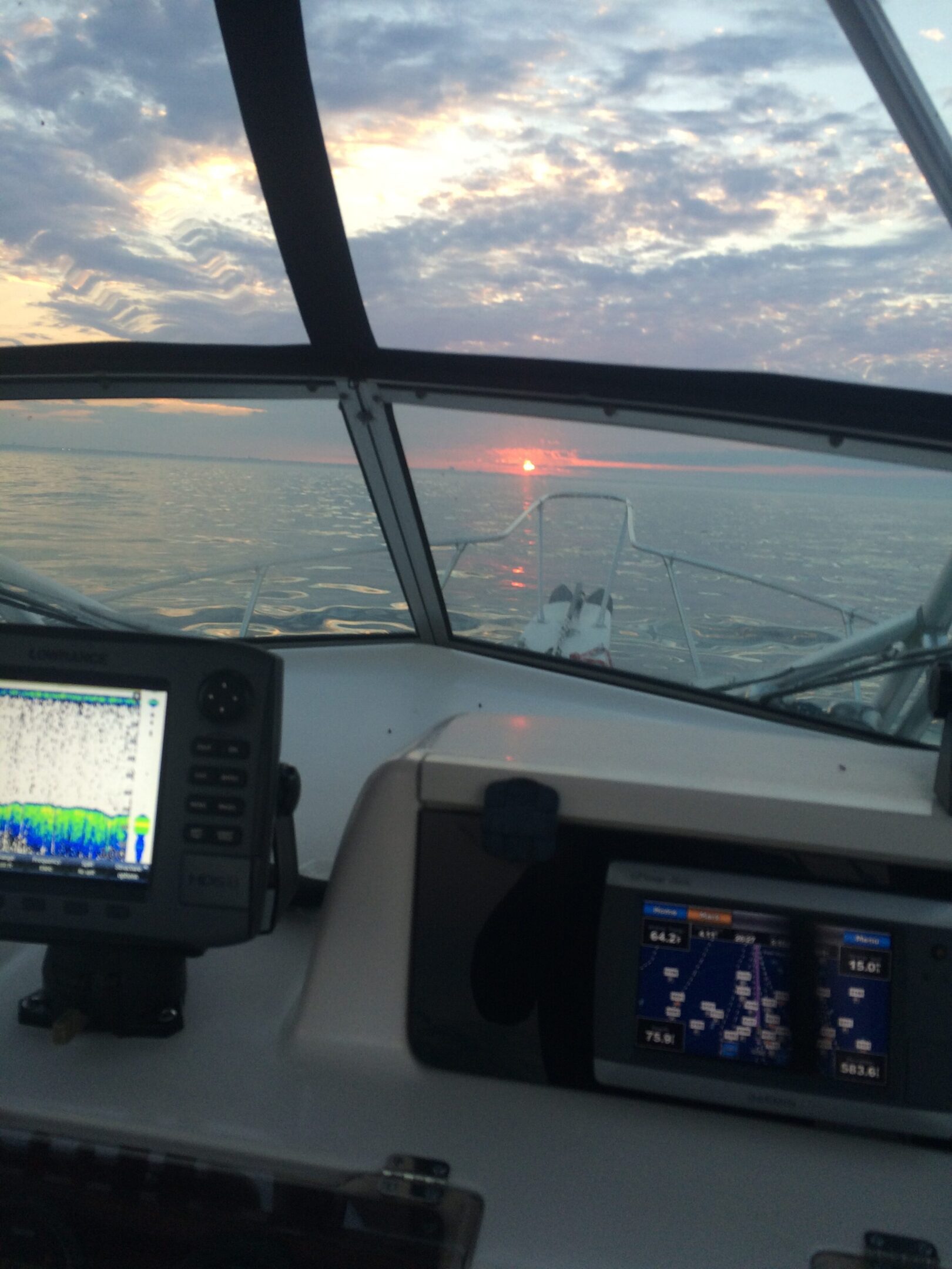 Sunset view from a boat cockpit with navigation screens.