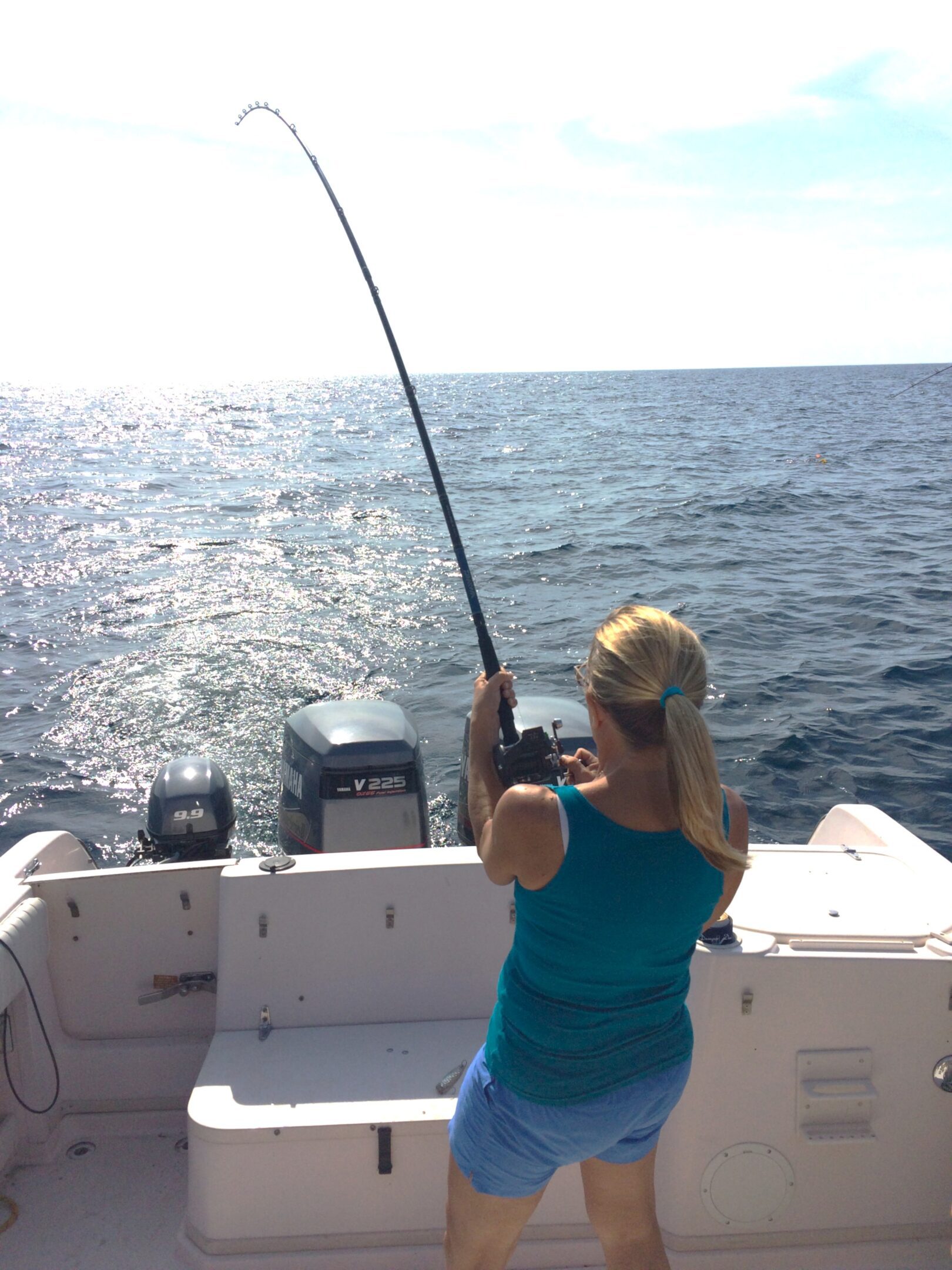A woman fishing on a boat in the ocean.