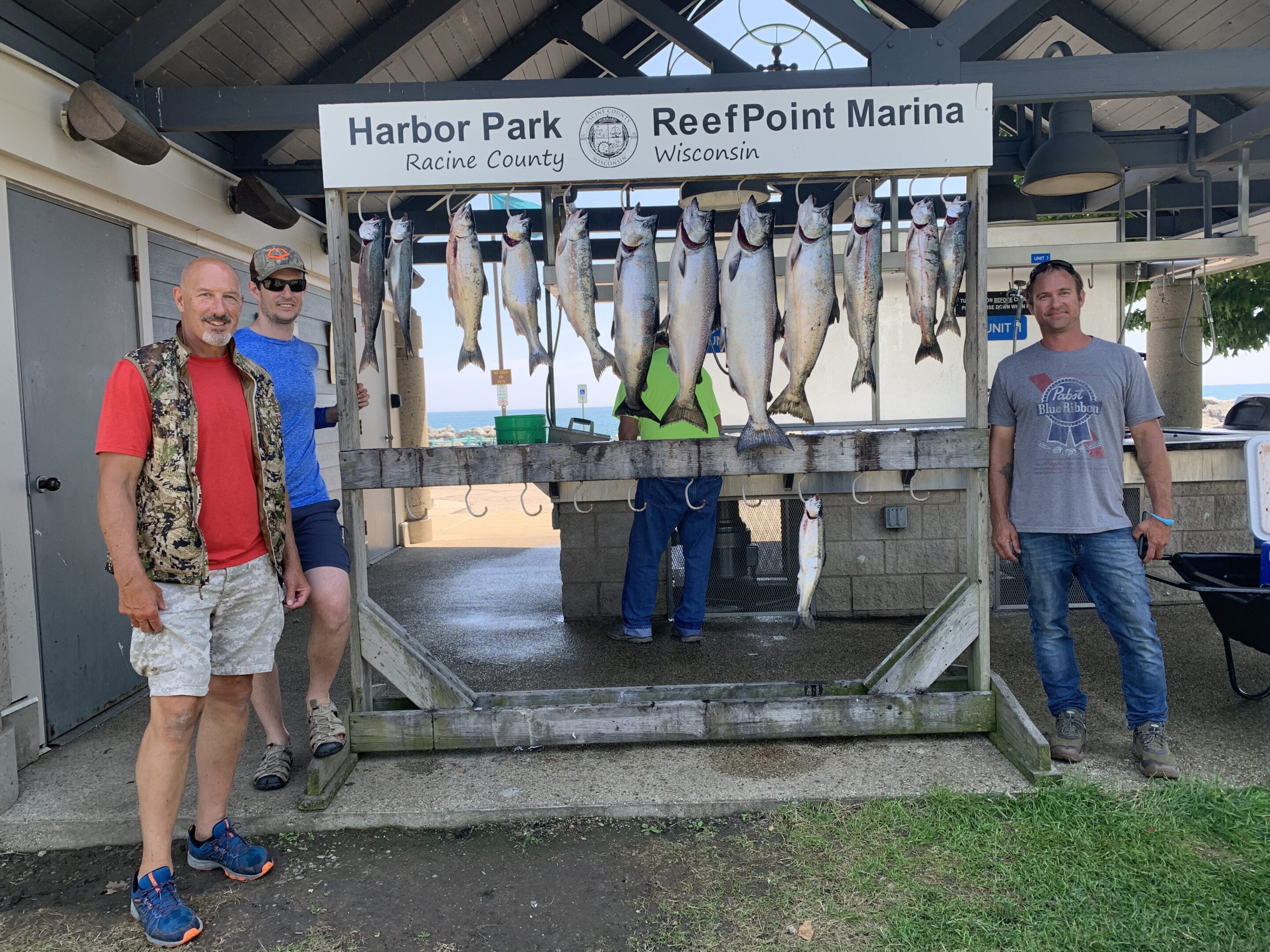 Two men standing beside a display of freshly caught fish at a marina.