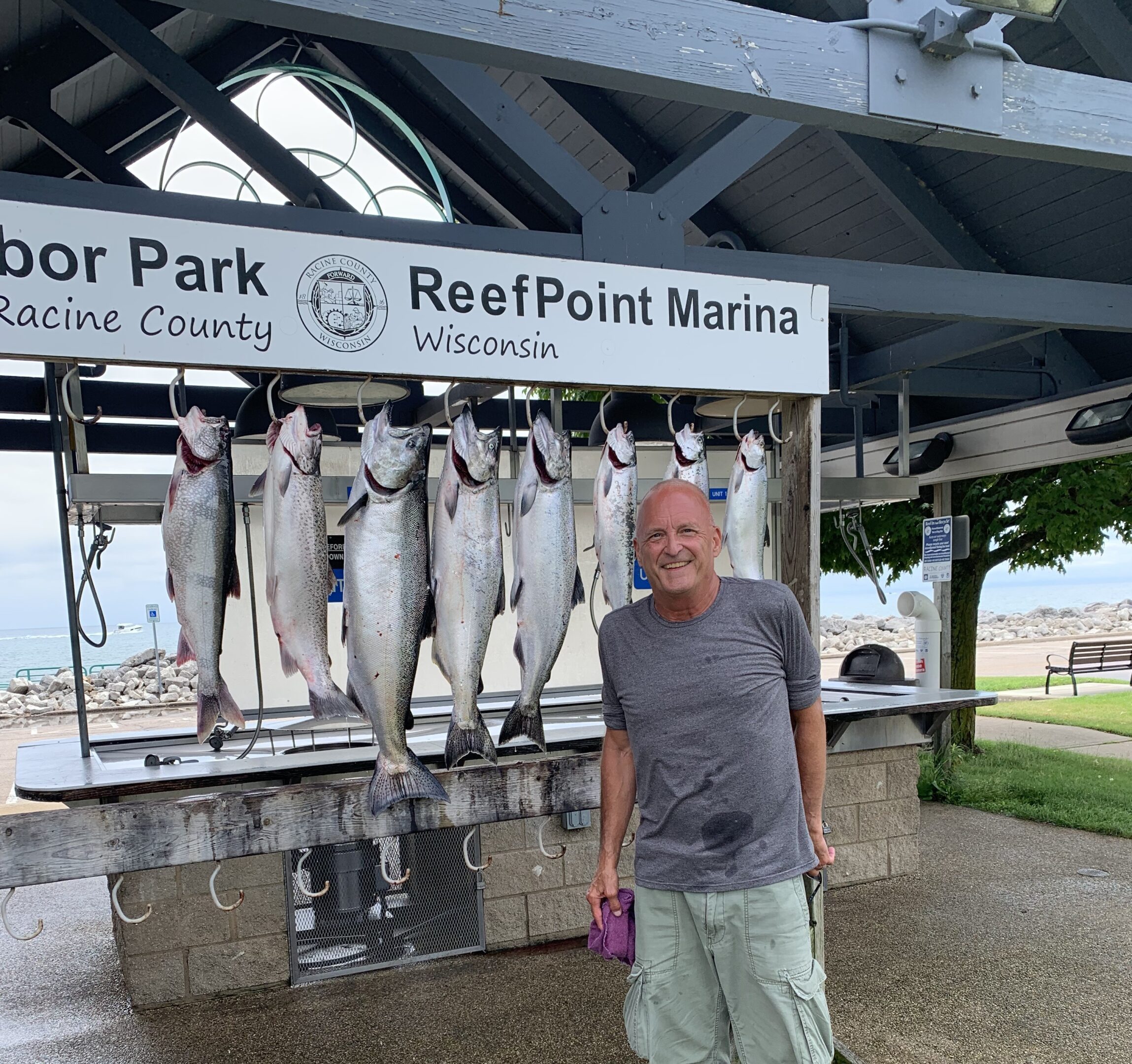 Man standing beside a display of freshly caught fish at ReefPoint Marina.