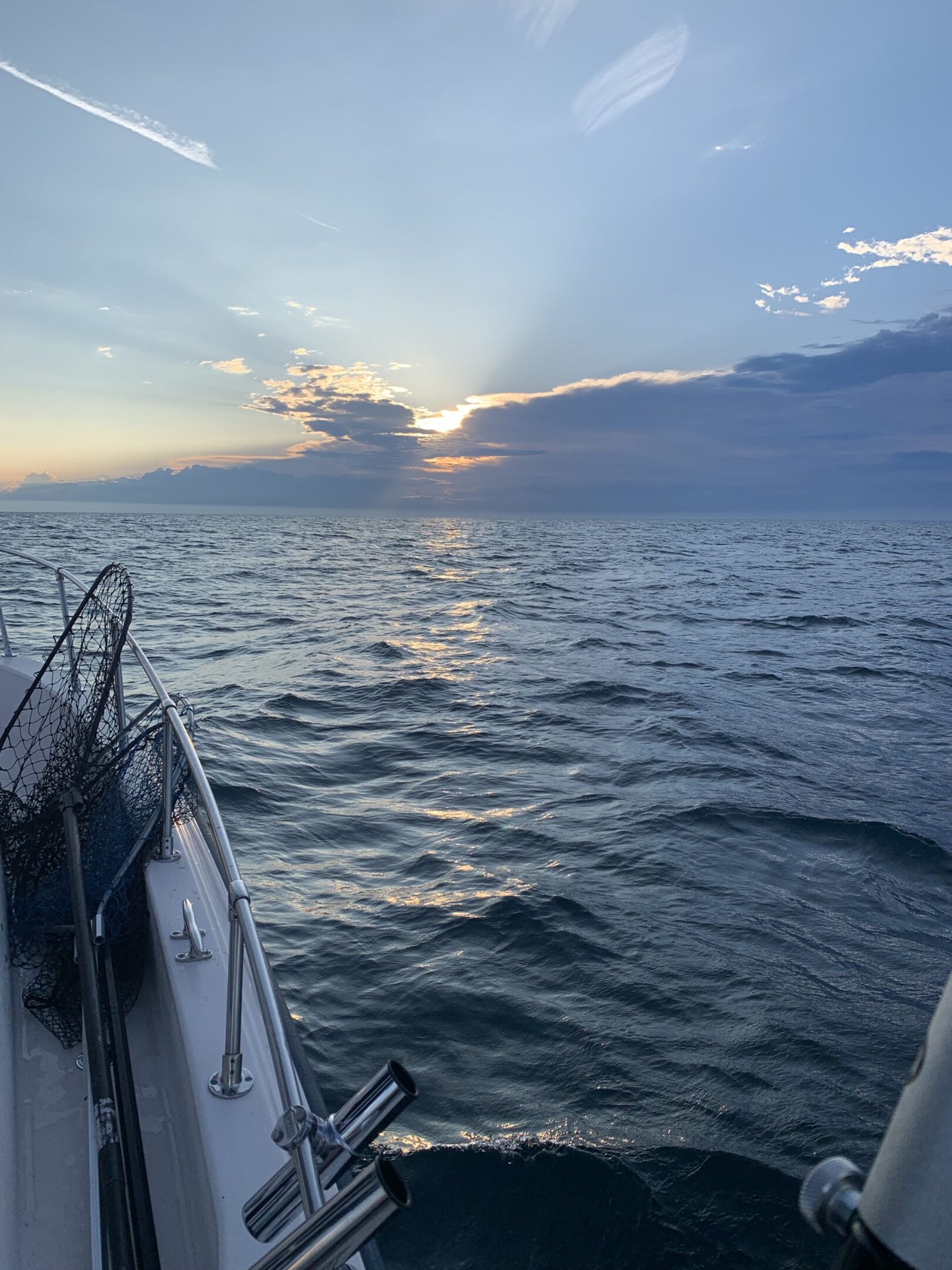 Sunset view over calm ocean from a boat deck.
