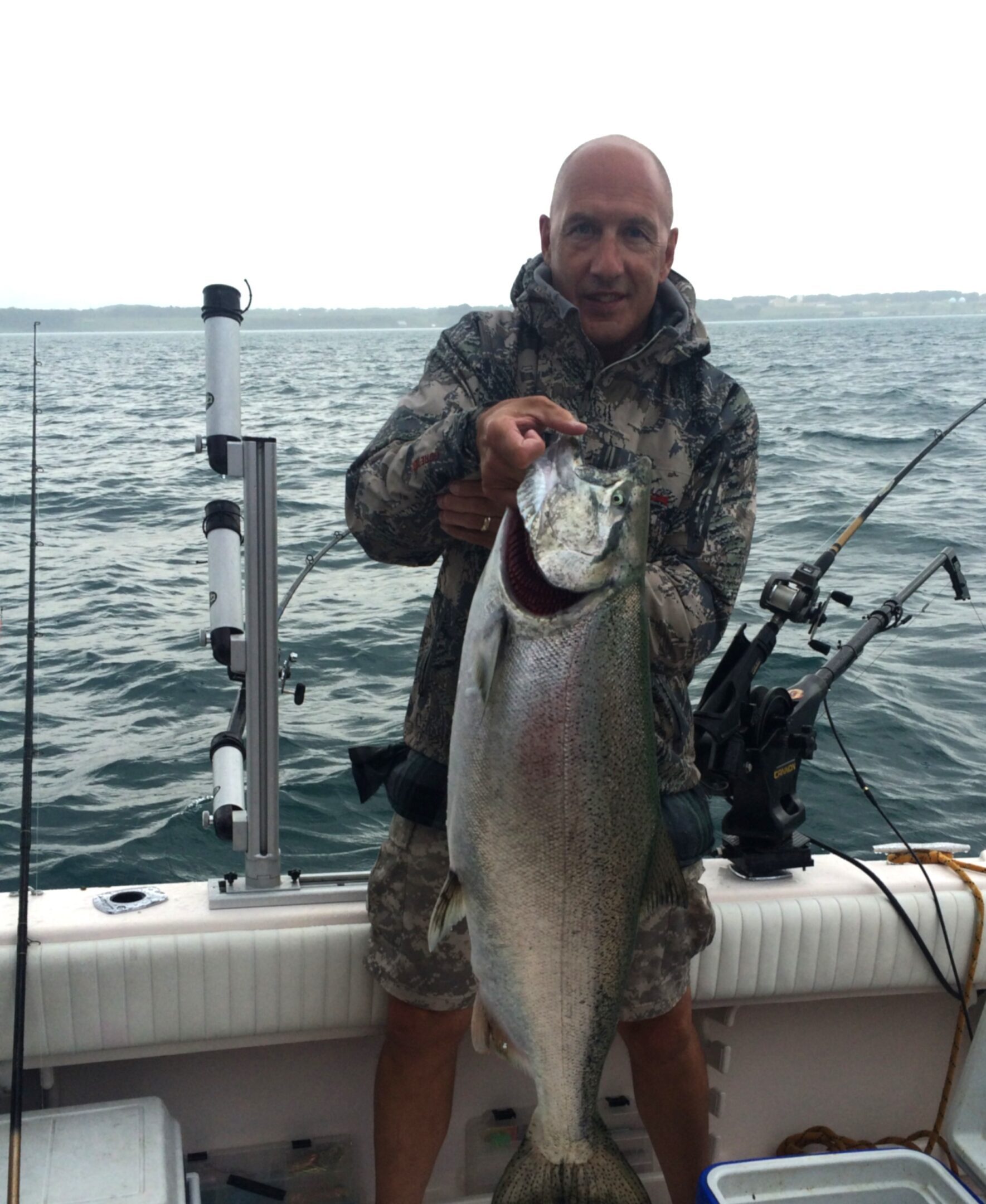 A man holding a large fish on a boat in the ocean.