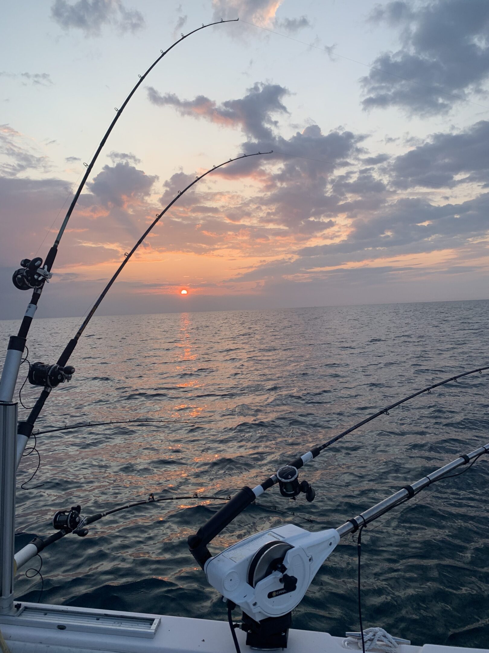 Sunset fishing with rods over calm ocean waters.