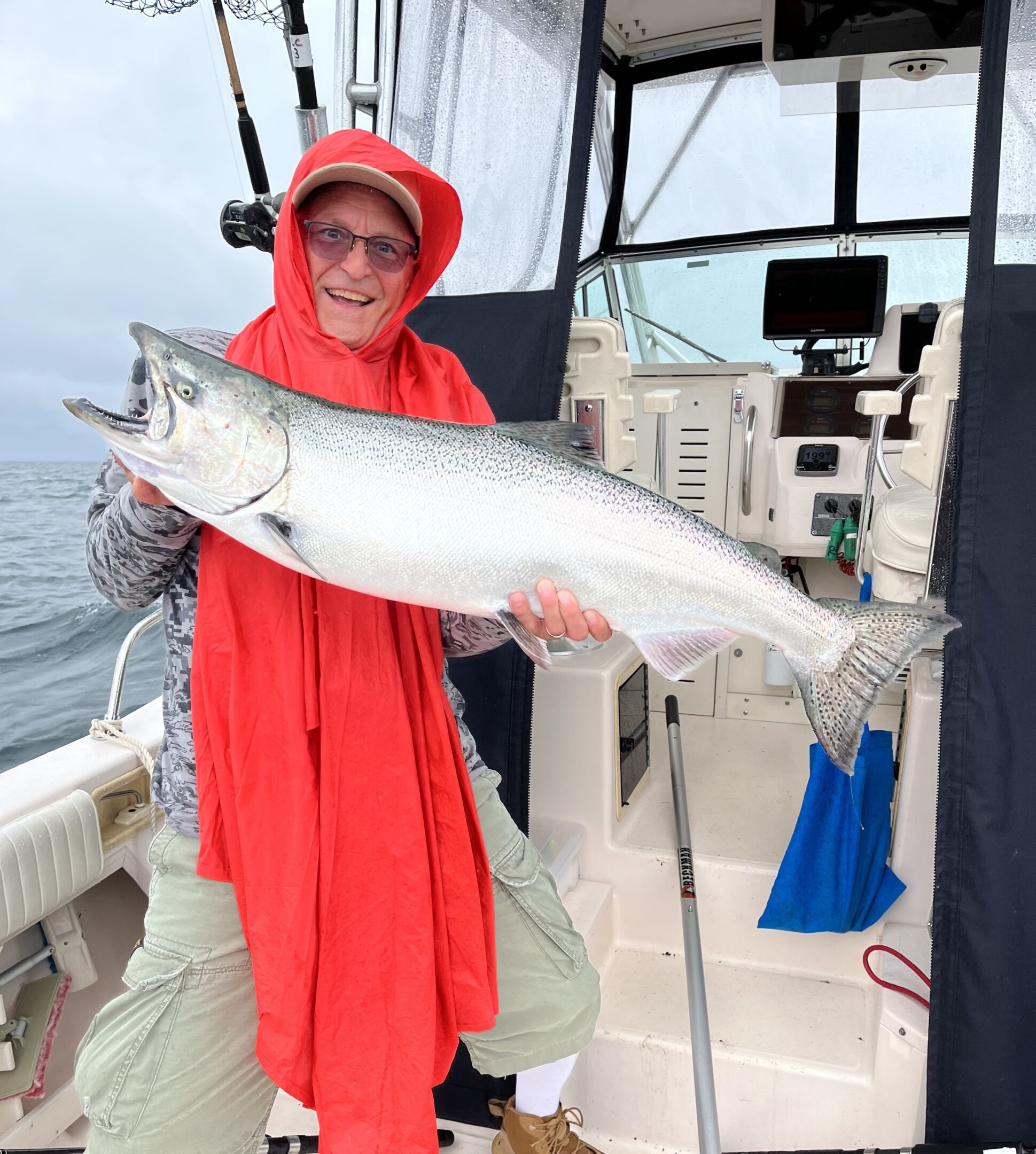 Person in red holding a large fish on a boat.