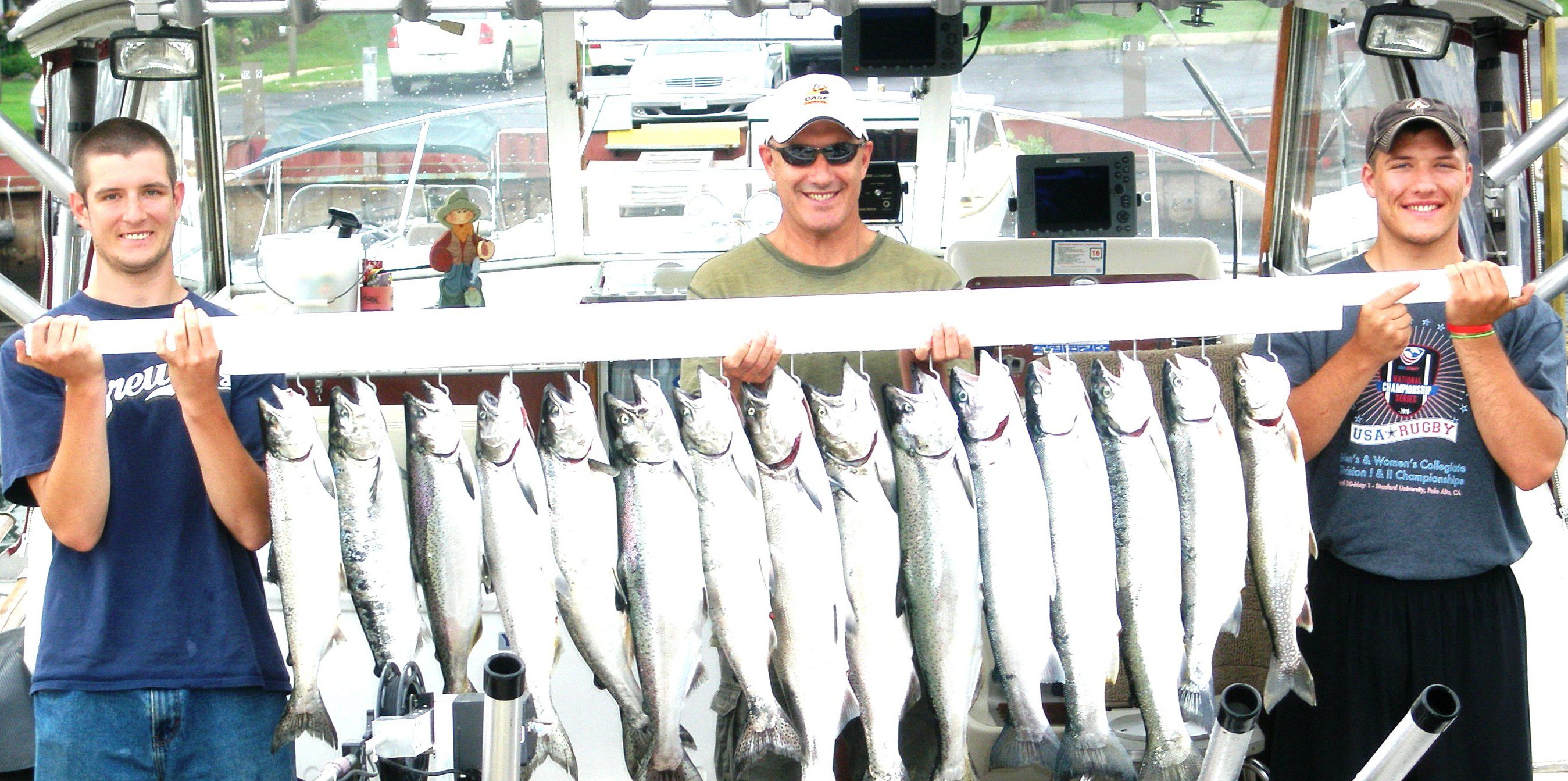 A man proudly displays a row of large caught fish.